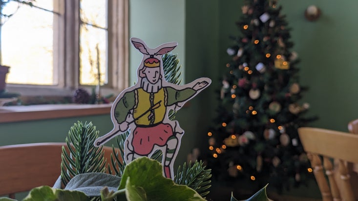 A small cut out of a Cartoon Tudor figure stands in front of a Christmas tree in Lyveden's cafe